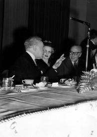 Portada:Plano medio de Arthur Rubinstein charlando con otras personas, sentados a la mesa