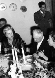 Portada:Plano medio de Arthur Rubinstein y Olga de Cadaval sentados a la mesa junto a otras personas