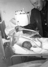 Portada:Plano general de Arthur Rubinstein observando a Alexander Coffin Rubinstein en una cuna del hospital