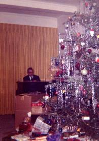 Portada:Plano medio de William Sloane Coffin sentado al piano, al fondo, detrás de un árbol de navidad