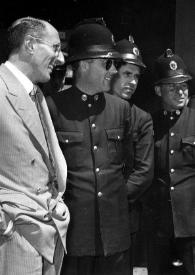 Portada:Plano medio de Arthur Rubinstein con sombrero y las gafas de sol en la mano junto a tres hombres con uniforme
