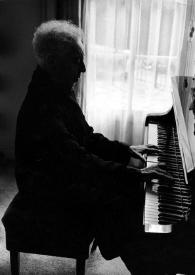 Portada:Plano general de Arthur Rubinstein (perfil derecho) sentado al piano. Fotografía tomada a contraluz