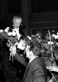 Portada:Plano general de Arthur Rubinstein recibiendo un ramo de flores de un hombre