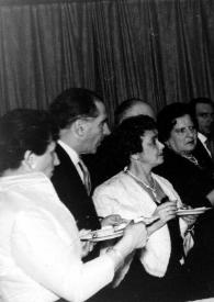 Portada:Plano medio de Arthur Rubinstein, con un plato en la mano, charlando con otros invitados
