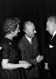 Portada:Plano medio de Arthur Rubinstein (perfil izquierdo) estrecha la mano de un hombre, en presencia de Aniela Rubinstein (perfil derecho), y de un periodista