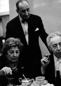 Portada:Plano medio de Arthur Rubinstein, con un puro en la mano, en el centro de la fotografía, sentado en una mesa junto a Ewa Bandrowska, el Señor Krukowski y Harry Neuhaus