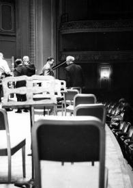 Portada:Plano medio de Arthur Rubinstein conversando con otros cuatro hombres sobre el escenario