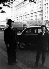 Portada:Plano general de Arthur Rubinstein, con sombrero, y un hombre posando delante de un coche