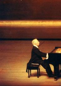 Portada:Plano general de Arthur Rubinstein (perfil derecho) sentado al piano, en el escenario. Fotografía tomada desde el fondo de la sala de conciertos.