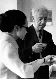 Portada:Plano medio de una mujer (traductora), Arthur Rubinstein y un hombre observando un libro de firmas.