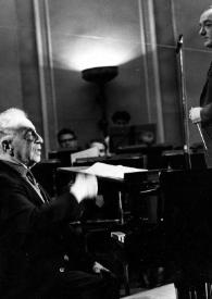 Portada:Plano medio de Arthur Rubinstein (perfil derecho) sentado al piano delante de János Ferencsik dirigiendo la orquesta