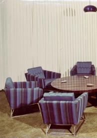 Portada:Plano general de la sala de estar de la Suite Rubinstein, con una mesa en el centro y seis sillones rodeándola.