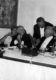 Portada:Plano medio de una mujer, Ben Gurion, Isaac Stern (de pie), Arthur Rubinstein, Aniela Rubinstein, Henry Haftel Zvi (de pie) y Señor Barzilai (Ministro de Sanidad Pública de Israel) sentados en la mesa.