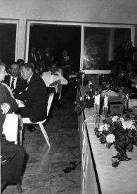 Portada:Plano general de la mesa desde un lateral, en el centro Arthur Rubinstein (de pie) brindando  mientras mira a la cámara, Alina Rubinstein y Señor Barzilai (Ministro de Sanidad Pública de Israel) sentados entre otros invitados