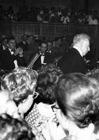 Portada:Plano medio de Arthur Rubinstein (perfil derecho) sentado al piano, la orquesta al fondo y el público delante
