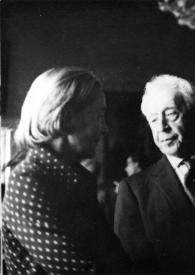 Portada:Plano medio de Arthur Rubinstein charlando con un hombre y una mujer, los dos de espaldas