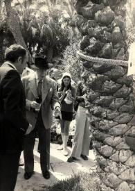 Portada:Plano general de Arthur Rubinstein observando las raíces de una palmera rodeado de gente