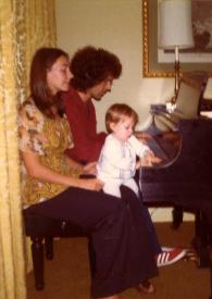 Portada:Plano general de Judith West (perfil derecho), John Rubinstein (perfil derecho) y Jessica Rubinstein (de frente) sentados al piano, Jessica sobre las rodillas de Judy tocando el piano