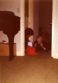 Portada:Plano medio de John Rubinstein (perfil derecho), Jessica Rubinstein (de espaldas) sentados en el suelo y Arthur Rubinstein tumbado en el suelo boca abajo jugando con Jessica