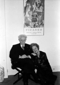 Portada:Plano general de Arthur Rubinstein sentado en una silla y Aniela Rubinstein a su lado sentada en el suelo posando