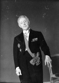 Portada:Plano general de Arthur Rubinstein posando, con medallas en la solapa del traje y banda