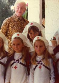 Portada:Plano general de Arthur Rubinstein posando con cinco niñas de la Cruz Roja vestidas de enfermeras