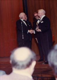 Portada:Plano general del embajador de Israel en Estados Unidos entregando un premio a Arthur Rubinstein, mientras J. J. Bistritzky y un hombreles observan detrás en el escenario