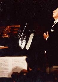 Portada:Plano general de Arthur Rubinstein (perfil izquierdo) sentado al piano, sujátandose las solapas de la chaqueta con las manos, mientras mira hacia arriba