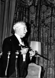 Portada:Plano general de Arthur Rubinstein (perfil izquierdo) sujetando entre sus manos una espada conmemorativa  y Bernard Gavoty observándole.