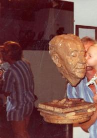 Portada:Plano general de un bebé sujeto en brazos de Kees Verkade besando el busto de Arthur Rubinstein