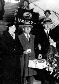 Portada:Plano general de Arthur y Aniela Rubinstein posando con dos ramos de flores entre las manos, junto a ellos, la delegación de bienvenida de Japón
