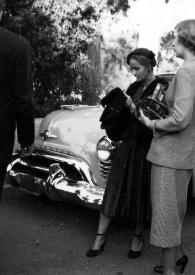Portada:Plano general de Aniela Rubinstein y una mujer charlando junto a un coche