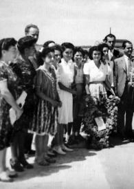 Portada:Plano medio de Arthur Rubinstein con un ramo de flores rodeado de personas posando