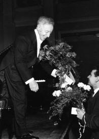 Portada:Plano general de Arthur Rubinstein recibiendo un ramo de flores en el escenario de manos de un hombre