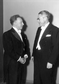 Portada:Plano general de Arthur Rubinstein (perfil derecho) charlando con un hombre (perfil izquierdo)