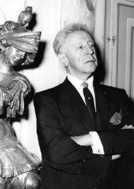 Portada:Plano medio de Arthur Rubinstein (medio perfil derecho) posando junto a una estatua de bronce