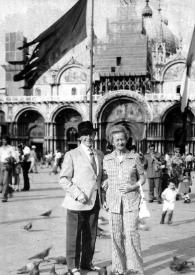 Portada:Plano general de Arthur y Aniela Rubinstein posando en la Plaza de San Marco rodeados de palomas
