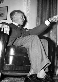 Portada:Plano general de Arthur Rubinstein (perfil derecho) sentado en un sillón charlando