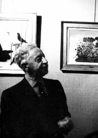 Portada:Plano medio de Arthur Rubinstein (medio perfil derecho) observando varios cuadros colgados en la pared de la sala de exposiciones