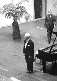 Portada:Plano general de Arthur Rubinstein de pie junto al piano saludando al público, detrás un hombre camina hacia él