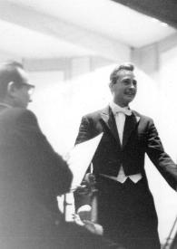 Portada:Plano general del director de la orquesta y Arthur Rubinstein cogidos de la mano saludando al publico