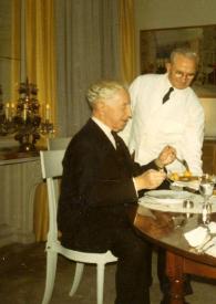 Portada:Plano general de Arthur Rubinstein sentado comiendo y Adam C. Kalinowski (camarero de la casa) sirviéndole la comida