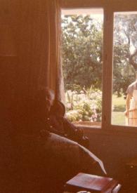 Portada:Plano general de Arthur Rubinstein sentado en una butaca junto a una ventana a traves de la cual se ve a una empleada de la casa limpiando