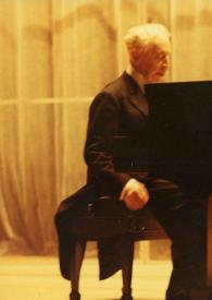 Portada:Plano general de Arthur Rubinstein (perfil derecho) sentado al piano.