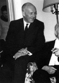 Portada:Plano general de un hombre, Arthur Rubinstein con un puro en la mano y una mujer sentados charlando y riendo