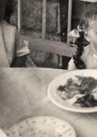 Portada:Plano medio de Eva Rubinstein sentada en una mesa posando, con la boca abierta, mientras alguien le da de comer