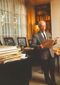 Portada:Plano general de Arthur Rubinstein de pie junto al piano, con chaqueta de pata de gallo y con un puro en la mano, mientras lee un libro
