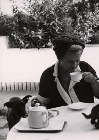 Portada:Plano medio de Aniela Rubinstein y Arthur Rubinstein sentados en una mesa tomando té y un gato pequeño negro andando por la mesa junto a las tazas. En el suelo, junto a Aniela Rubinstein, está Café, el perro de la familia Rubinstein