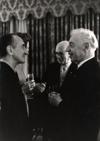 Portada:Plano medio de Arthur Rubinstein con una copa en la mano derecha charlando con Leonard Lyons, al fondo Sol Hurok