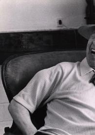 Portada:Plano medio de Arthur Rubinstein (perfil izquierdo) con sombrero, sentado en un sofá, riendo y fumando un puro